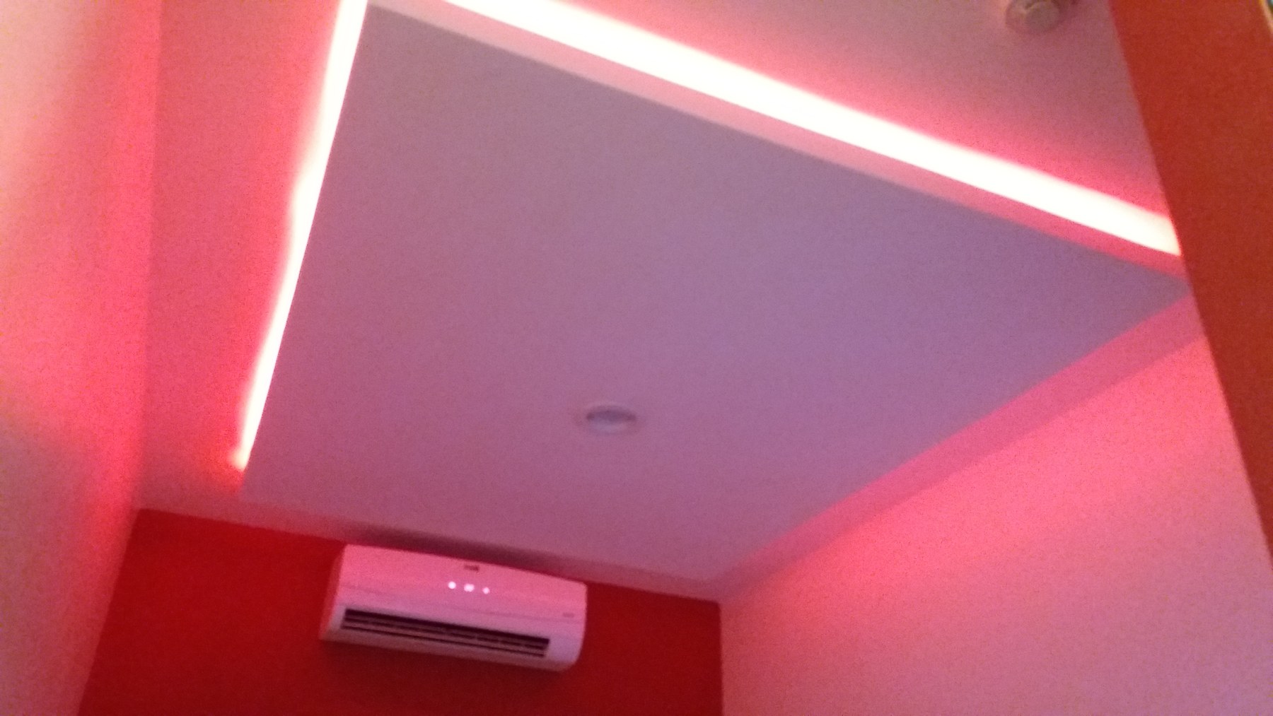 Cielo raso con bandeja e iluminación LED perimetral en ambiente de paredes rojas · MÁS VIDRIOS
