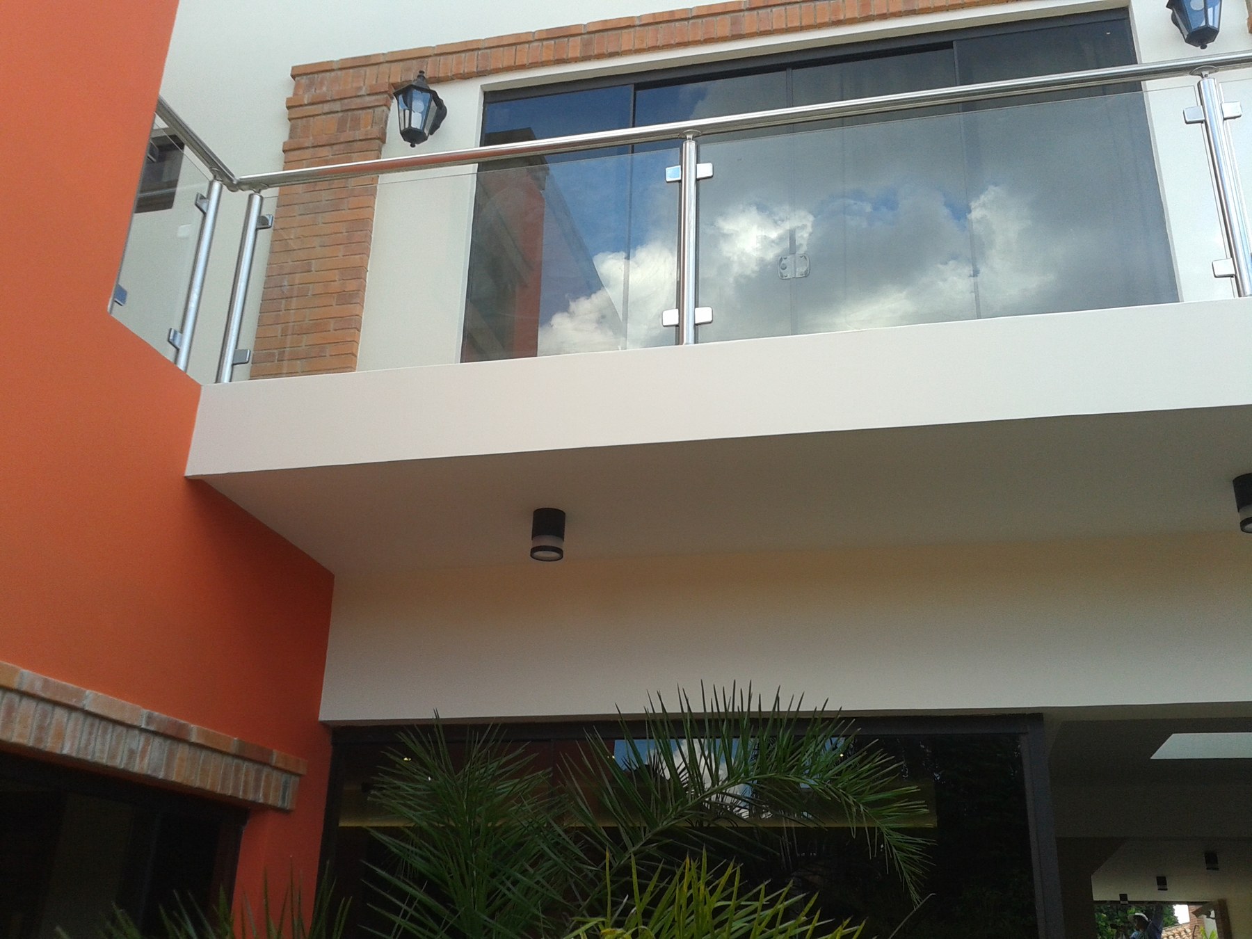 Baranda de vidrio con parantes y pasamanos de acero inoxidable en balcón de vivienda · MÁS VIDRIOS