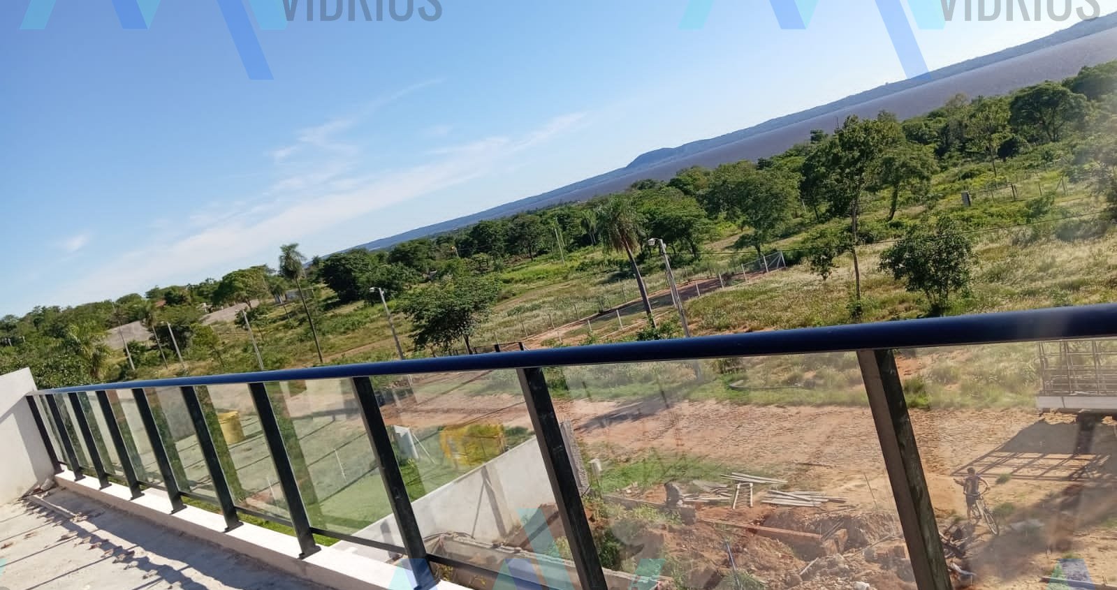 Baranda de vidrio con parantes y pasamanos de aluminio negro en balcón con vista al lago · MÁS VIDRIOS