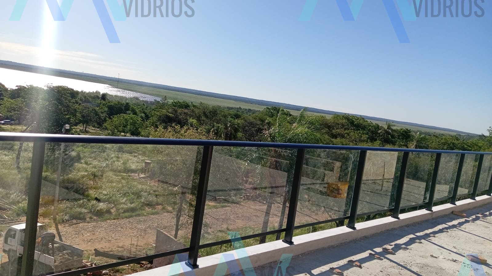 Baranda de vidrio con perfilería de aluminio negro en terraza panorámica sobre el río · MÁS VIDRIOS