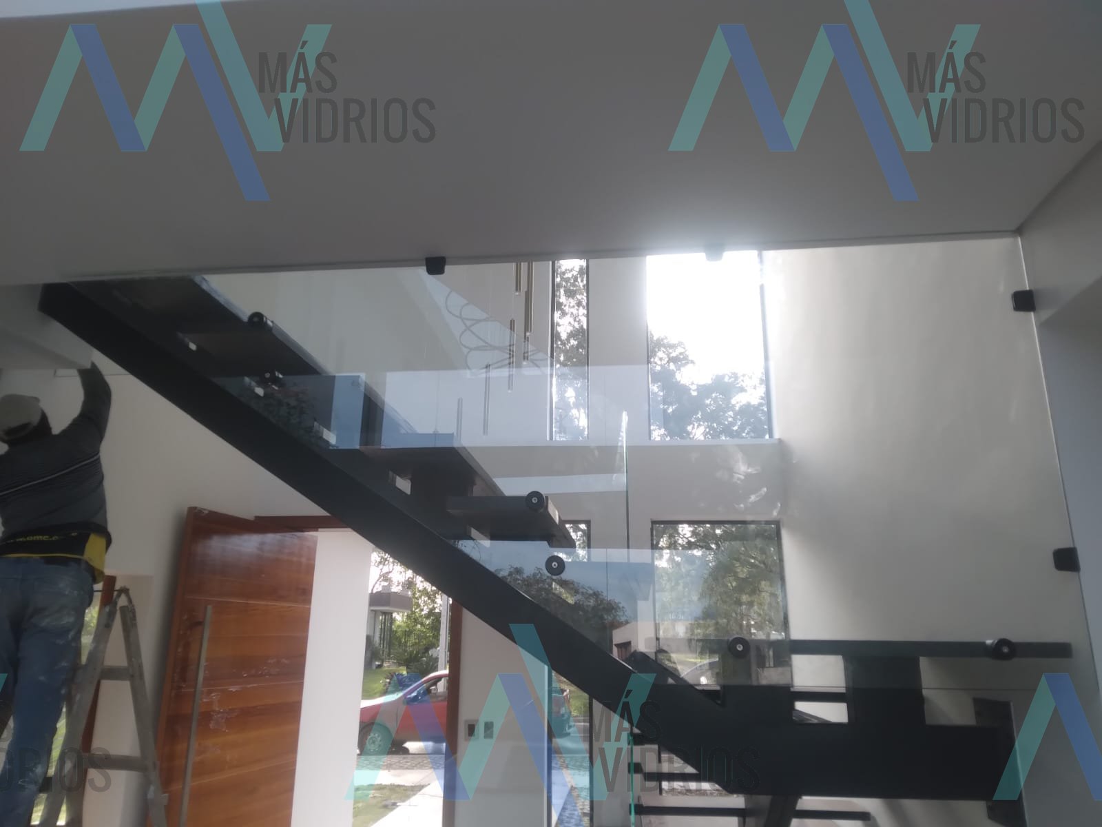 Baranda de vidrio templado con botones sobre escalera metálica negra · MÁS VIDRIOS