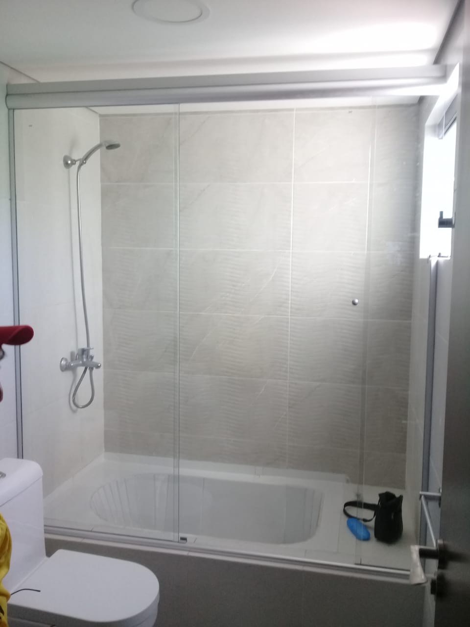 Box de ducha corredizo sobre receptáculo en baño blanco terminado · MÁS VIDRIOS