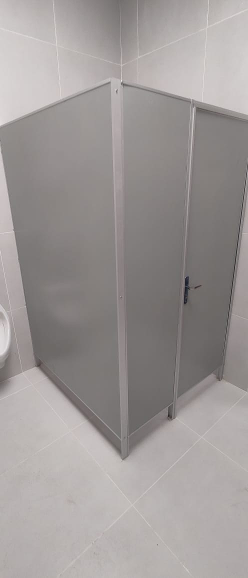 Cabina de sanitario con placas Eucatex gris y perfilería de aluminio en baño de porcelanato · MÁS VIDRIOS