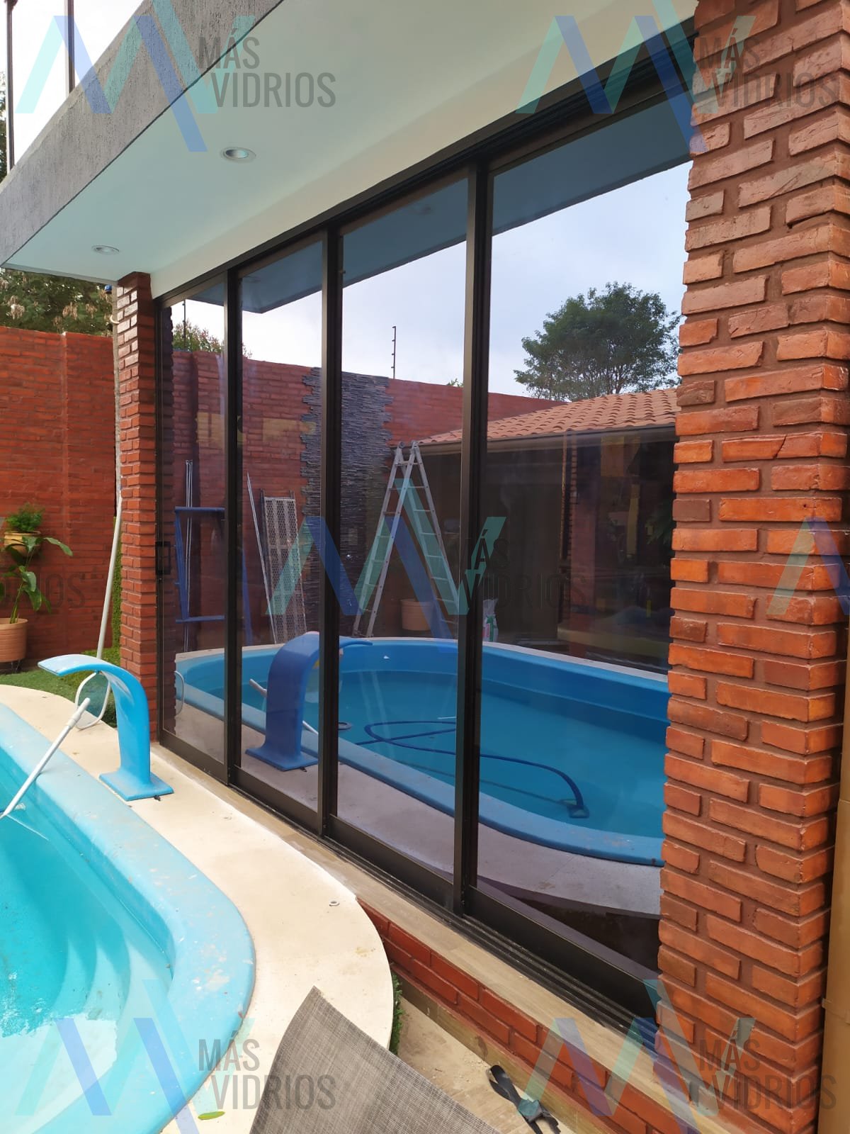 Cerramiento de vidrio con perfiles de aluminio negro junto a piscina · MÁS VIDRIOS