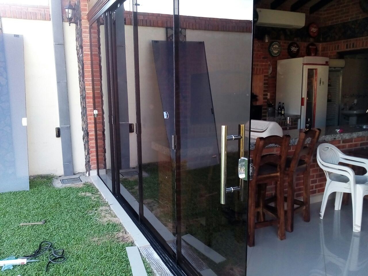 Paños corredizos de vidrio templado sin marco cerrando un quincho, con tirador vertical a la vista · MÁS VIDRIOS
