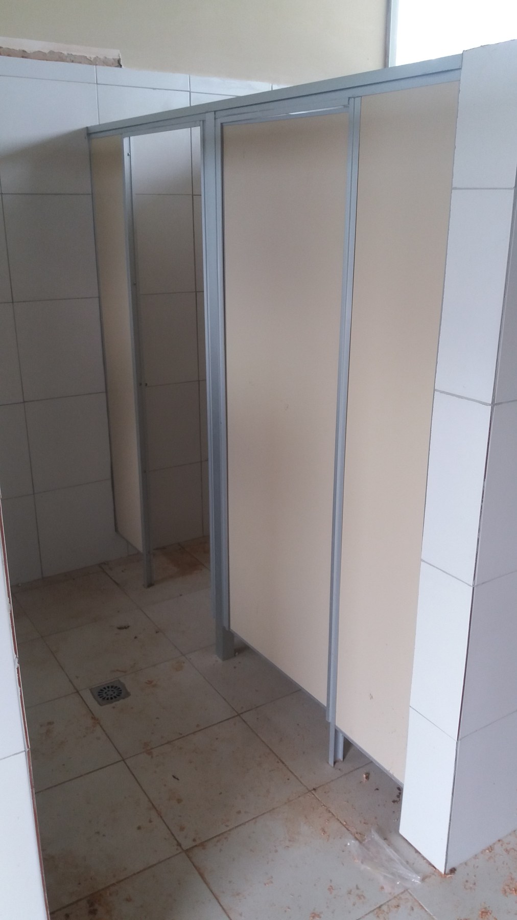 Divisiones de sanitarios en placas Eucatex claras con perfilería de aluminio en baño de porcelanato · MÁS VIDRIOS