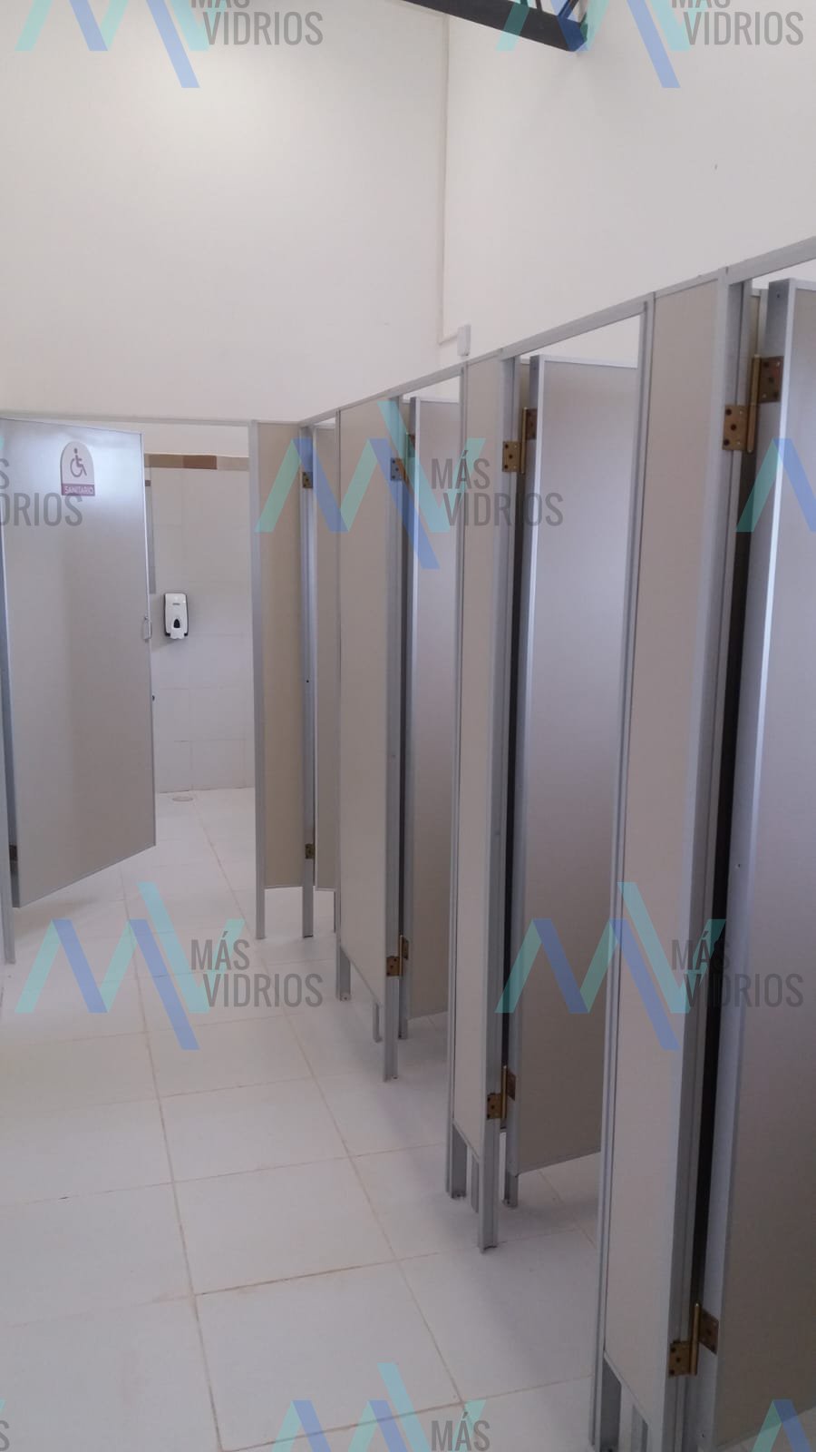 Cabinas de sanitario en Eucatex con perfilería de aluminio en un baño público · MÁS VIDRIOS