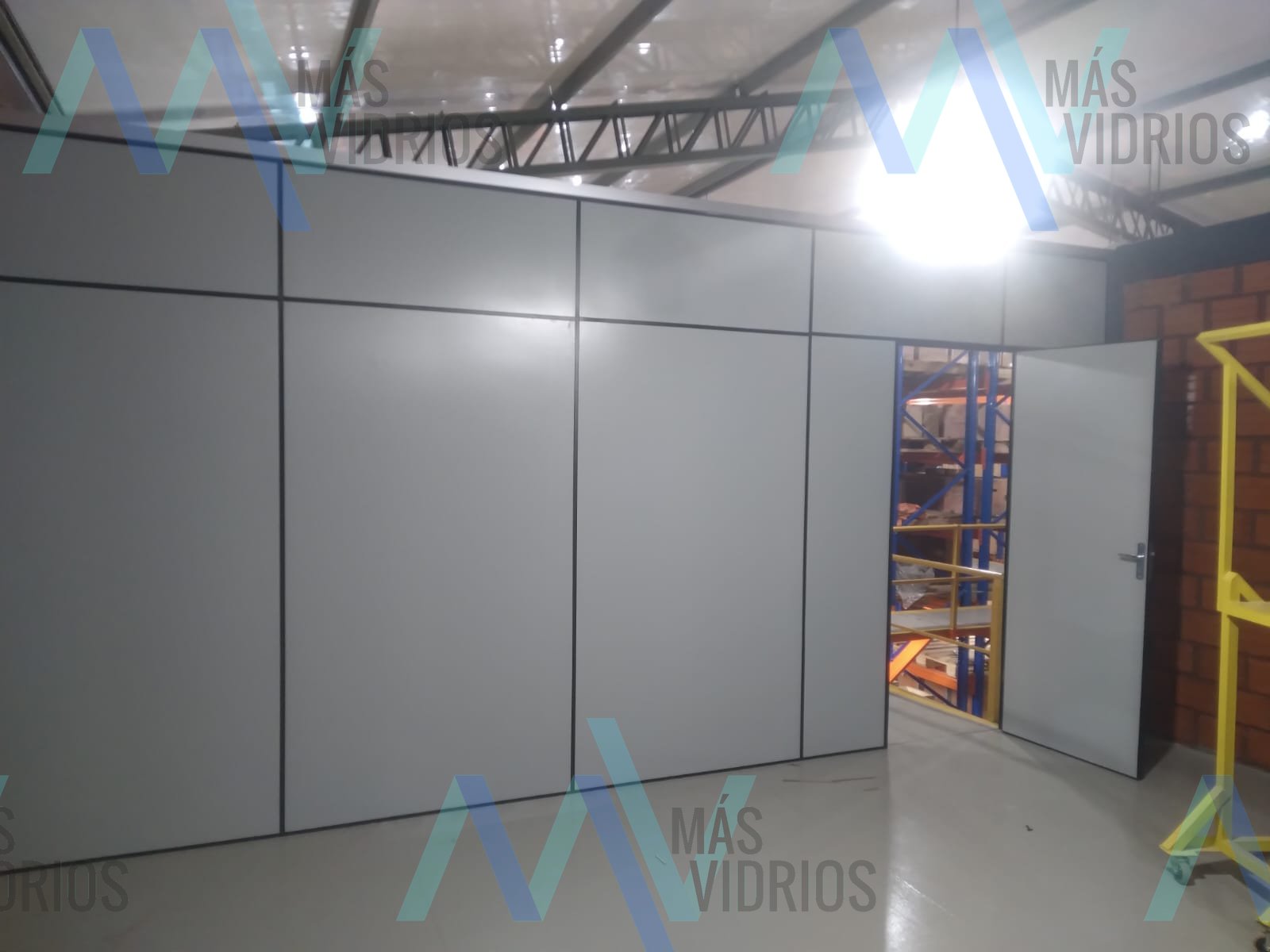 Divisoria de Eucatex gris con puerta cerrando un sector de depósito · MÁS VIDRIOS