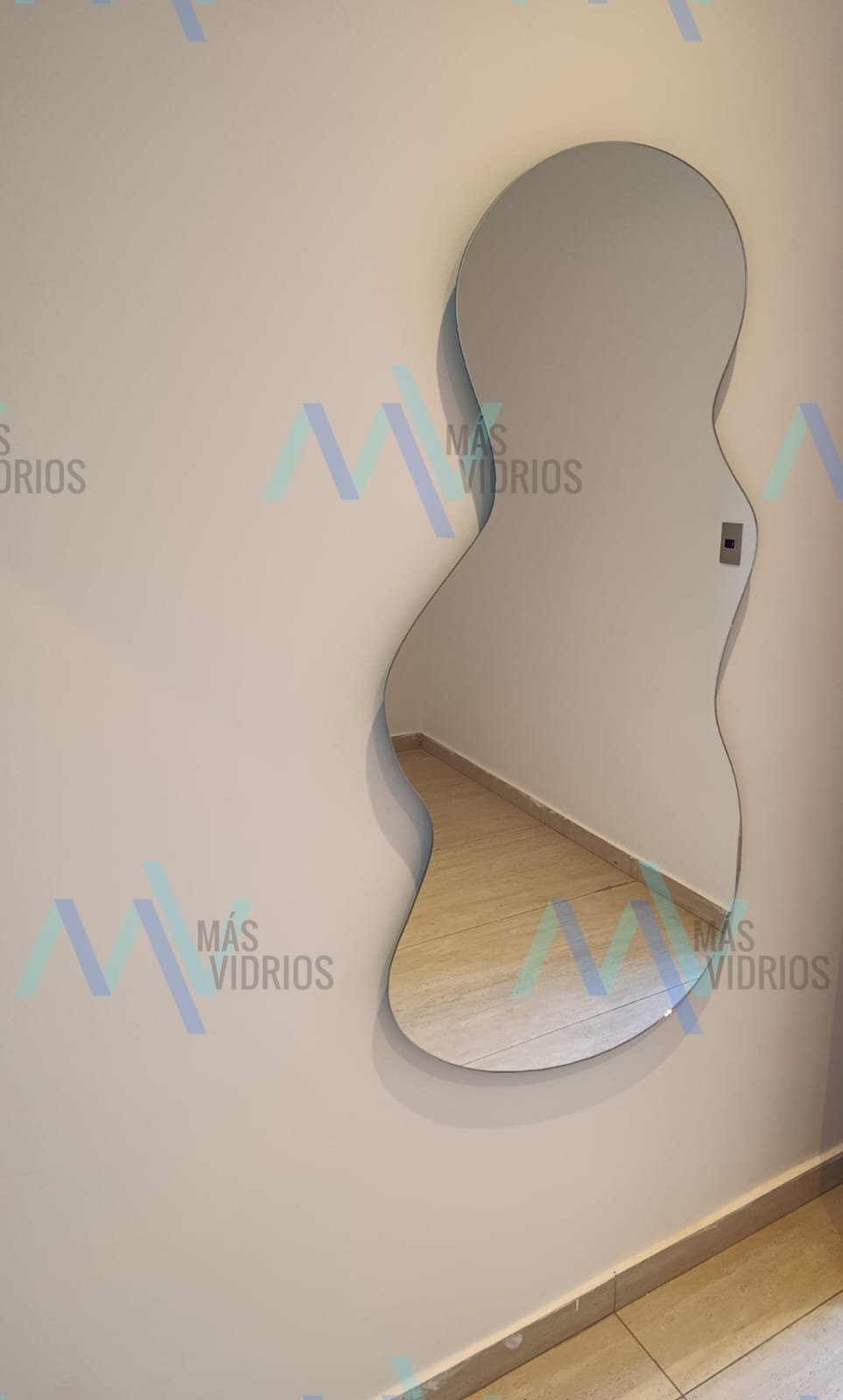 Espejo decorativo de forma orgánica sin marco instalado en pared interior de vivienda · MÁS VIDRIOS