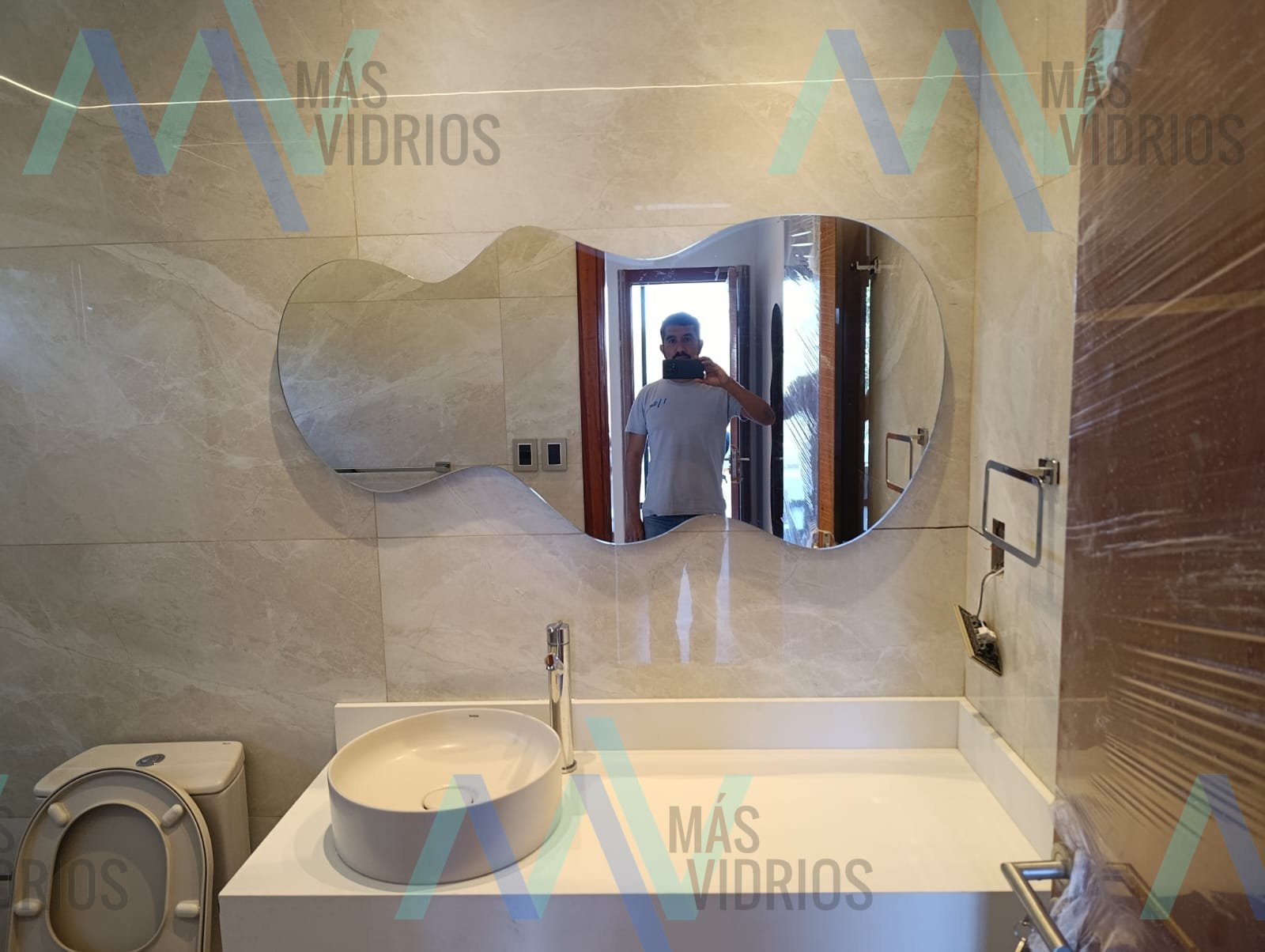 Espejo de forma orgánica sin marco en baño moderno · MÁS VIDRIOS