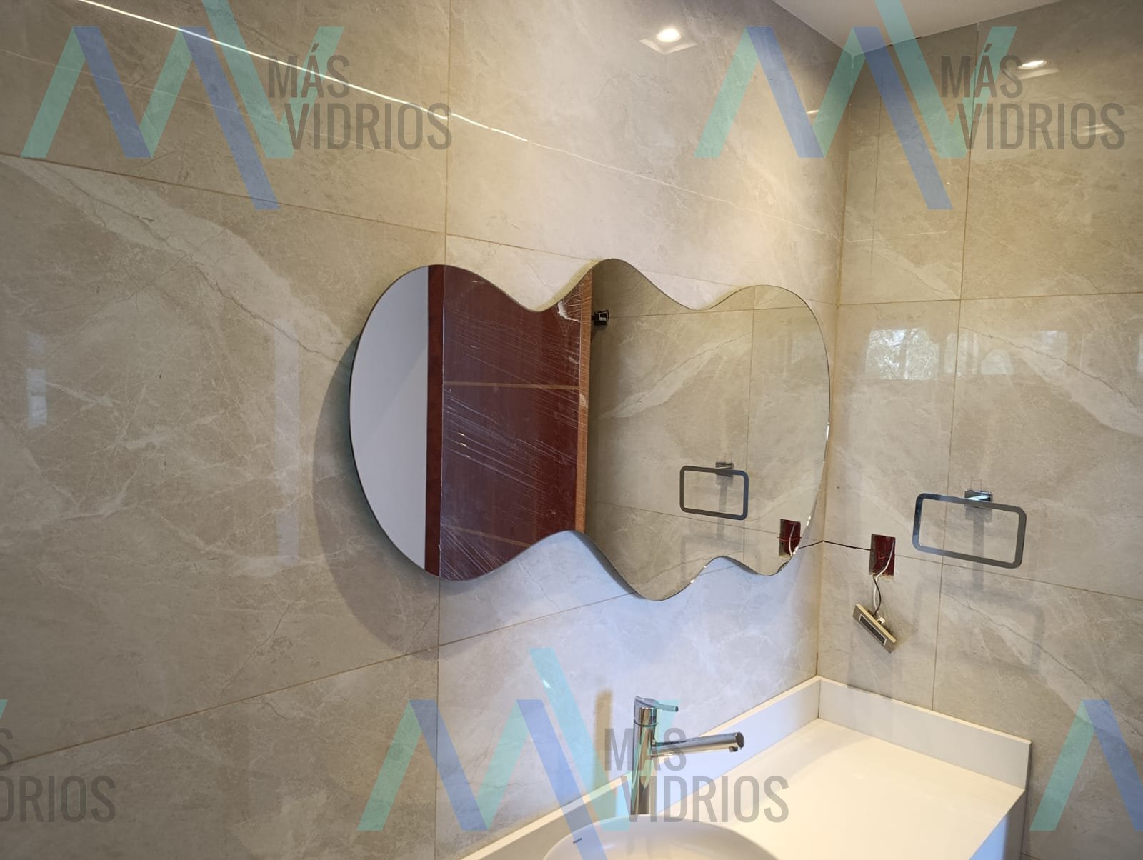 Espejo de forma orgánica sin marco sobre bacha en baño moderno · MÁS VIDRIOS