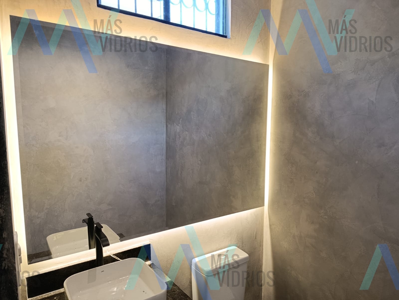 Espejo retroiluminado con LED sobre mesada de granito en baño moderno · MÁS VIDRIOS