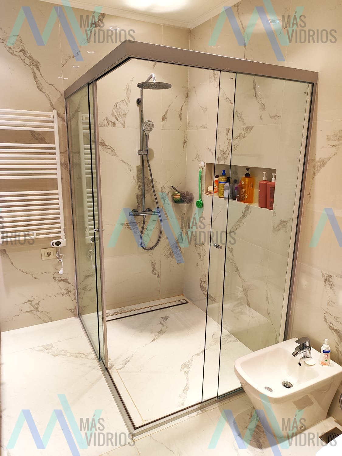 Mampara de ducha esquinera de vidrio con puertas corredizas en baño de mármol · MÁS VIDRIOS