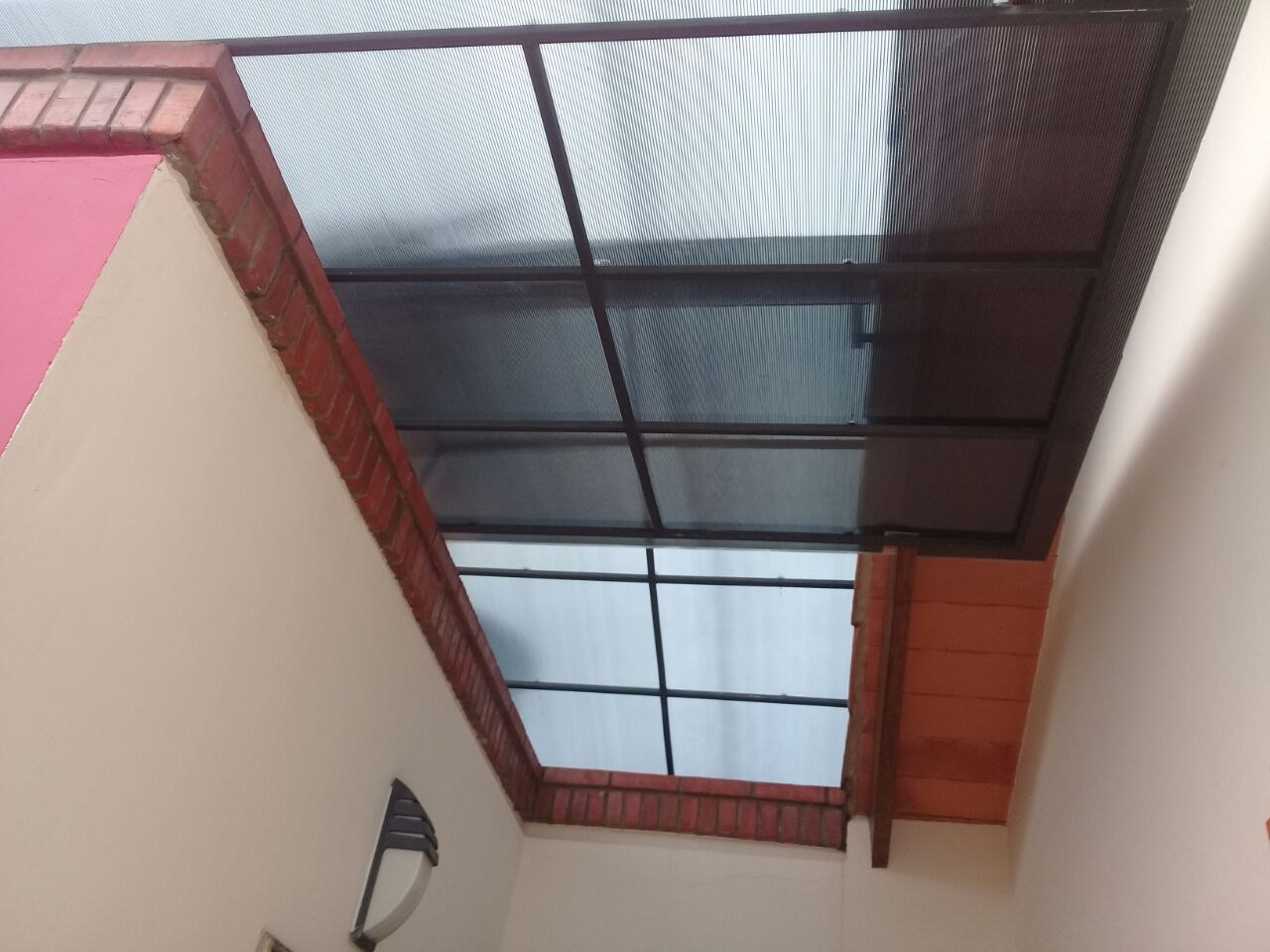 Techo de policarbonato alveolar sobre patio interno visto desde abajo con su estructura metálica · MÁS VIDRIOS