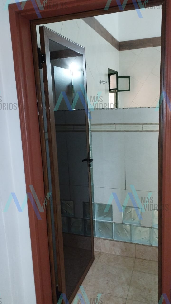 Puerta de aluminio símil madera con vidrio tonalizado y bloques de vidrio en baño · MÁS VIDRIOS