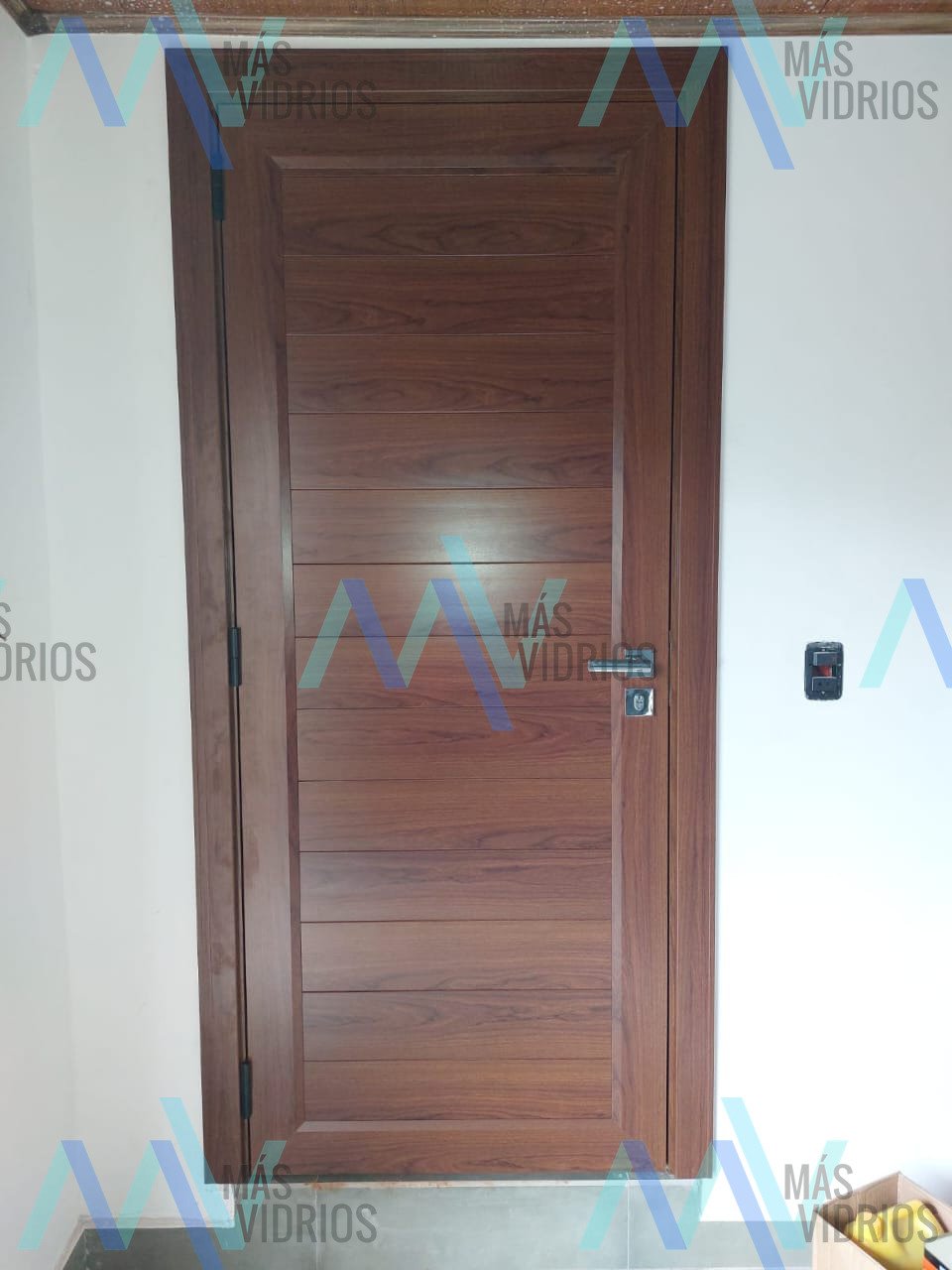 Puerta batiente interior con terminación símil madera y herrajes metálicos · MÁS VIDRIOS