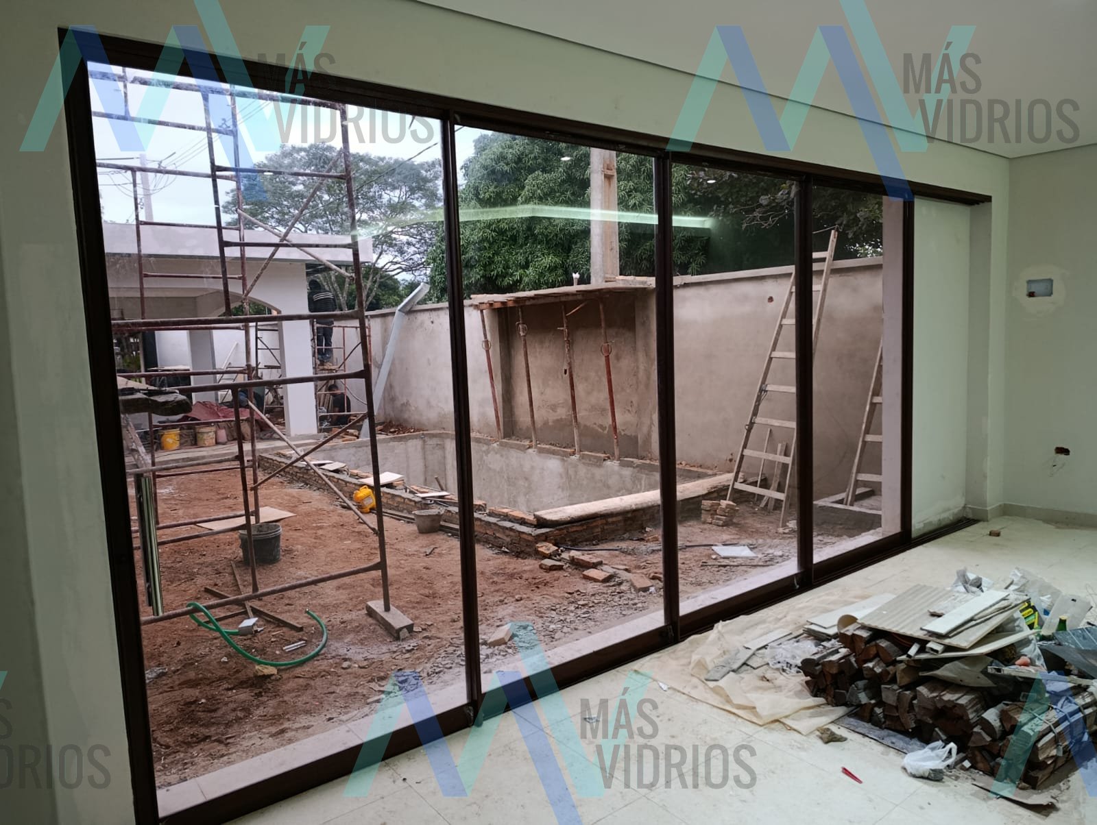 Puerta corrediza de aluminio de cuatro hojas con vidrio de piso a techo en vivienda en construcción · MÁS VIDRIOS