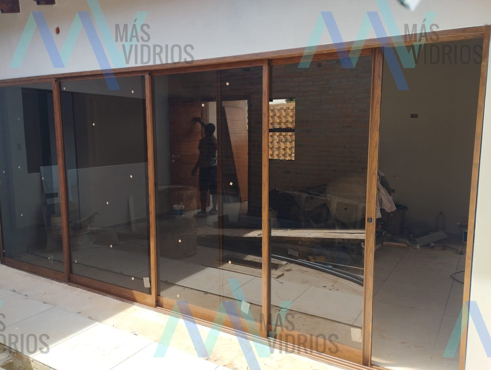 Puerta corrediza de aluminio símil madera con vidrio bronce en obra residencial · MÁS VIDRIOS