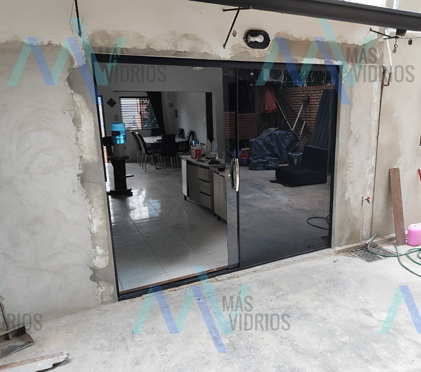 Puerta corrediza de vidrio templado fumé con perfiles negros en vivienda · MÁS VIDRIOS