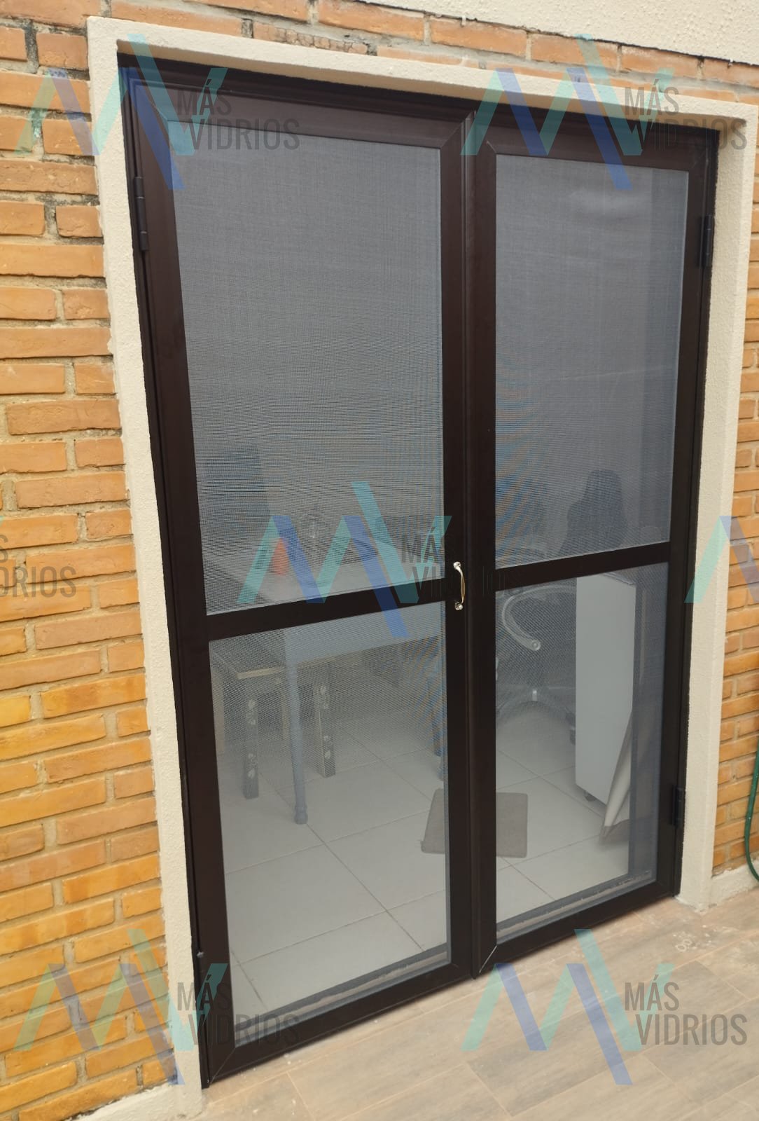 Puerta doble de aluminio con mosquitero instalada en muro de ladrillo visto · MÁS VIDRIOS
