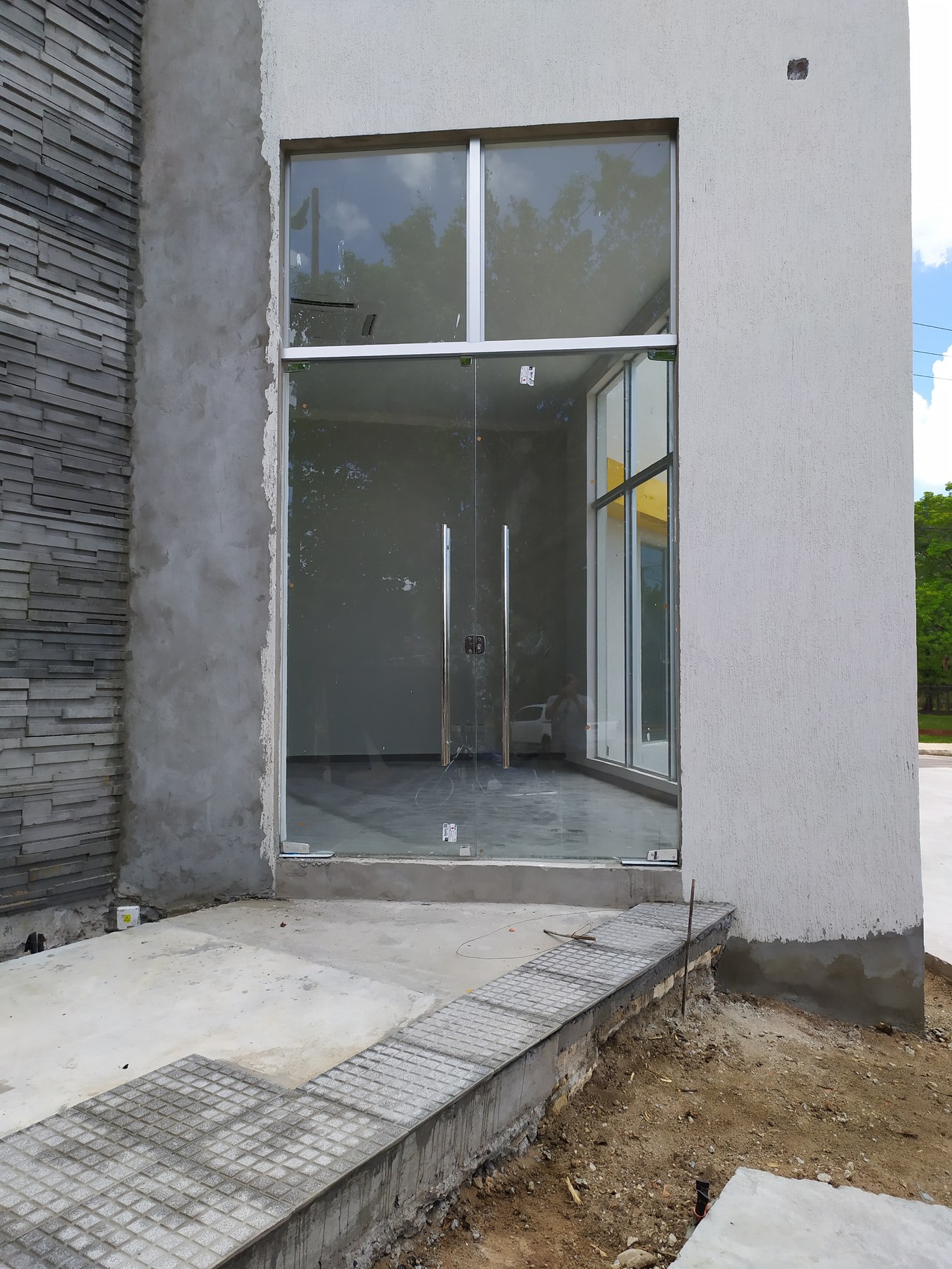 Puerta doble de vidrio templado con tiradores tubulares en el acceso de un local · MÁS VIDRIOS