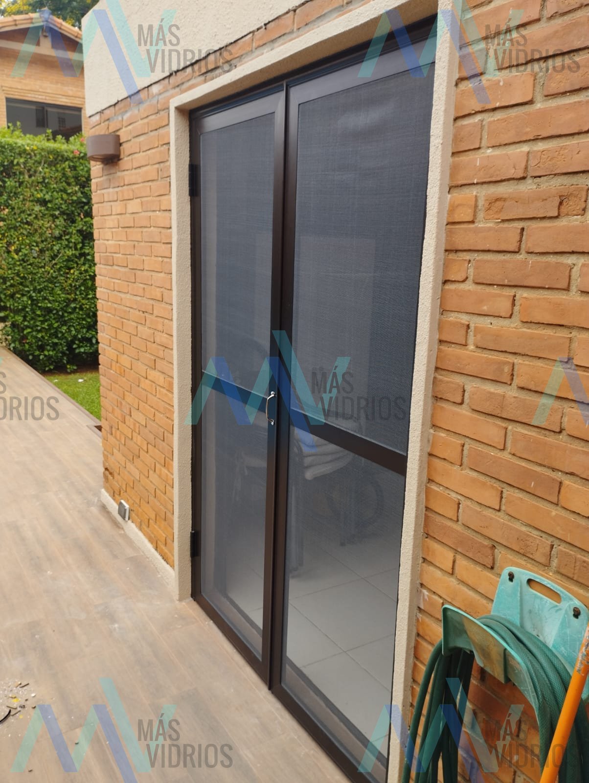 Puerta mosquitero doble de aluminio en patio de vivienda · MÁS VIDRIOS