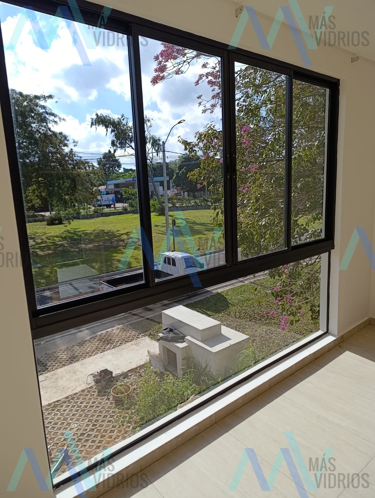 Ventanal corredizo de aluminio negro con paños fijos y vista al jardín · MÁS VIDRIOS