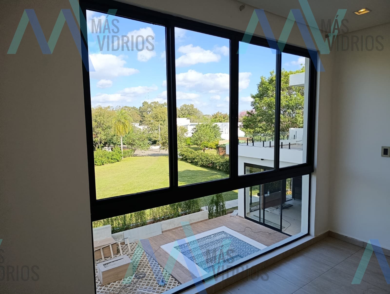 Ventanal corredizo de aluminio negro con vista al jardín en casa moderna · MÁS VIDRIOS