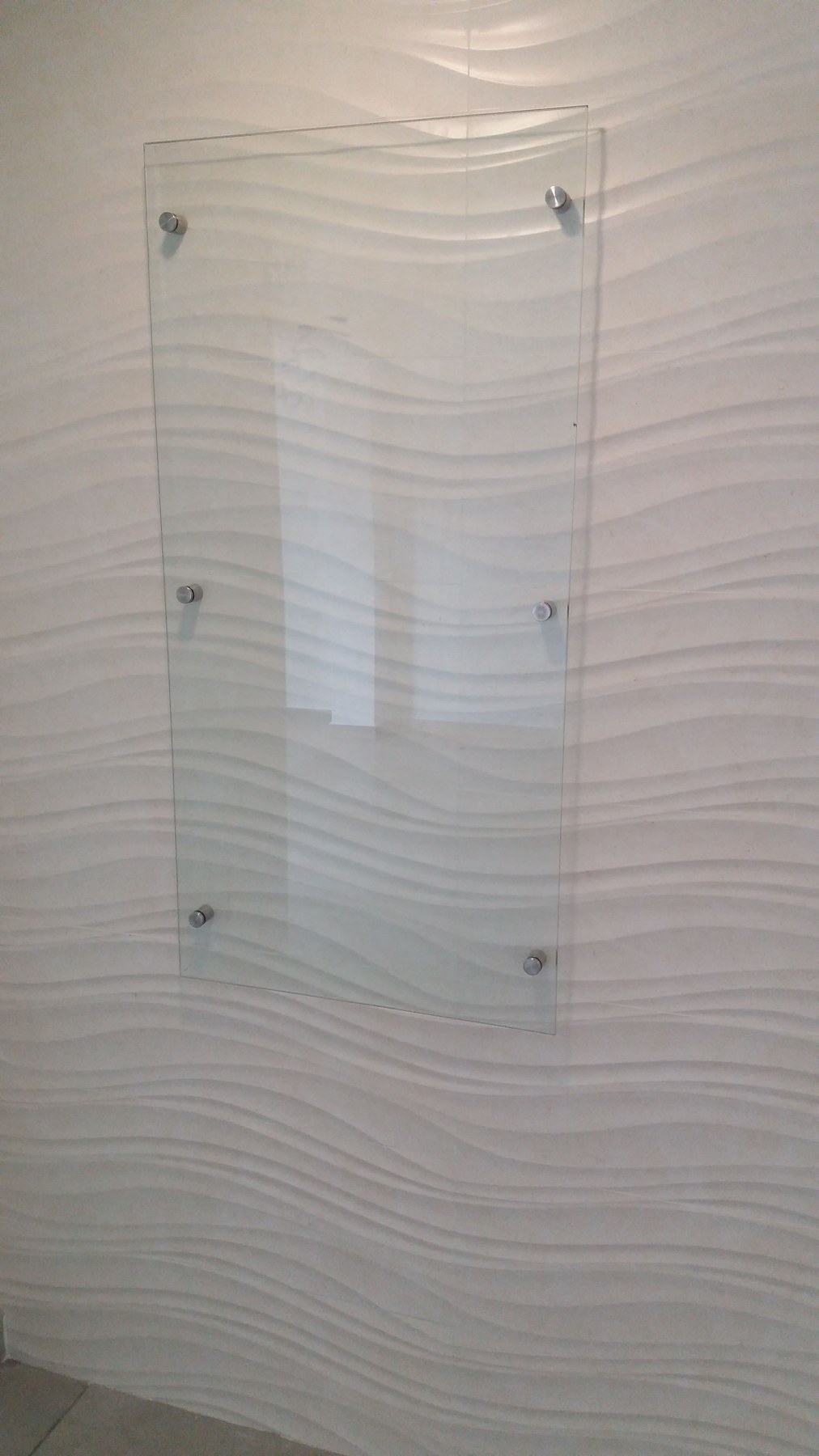 Paño de vidrio fijado con botones sobre pared texturada · MÁS VIDRIOS