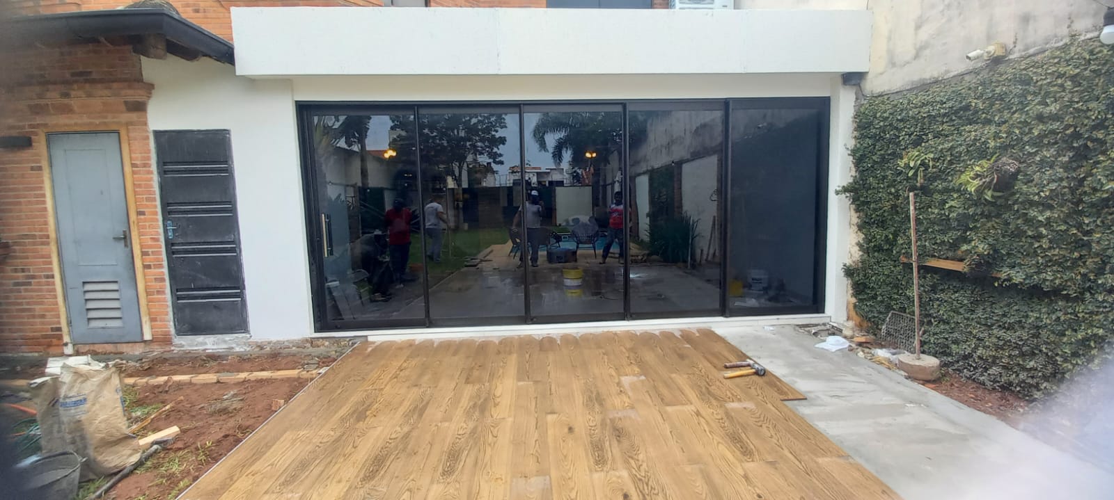 Cerramiento de quincho con vidrio y aluminio negro, deck de madera · MÁS VIDRIOS