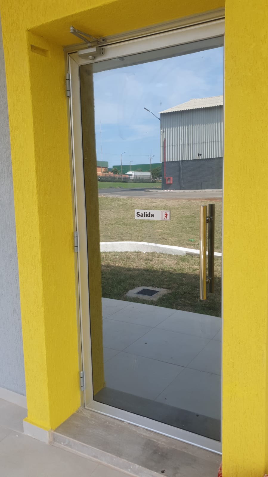 Puerta de vidrio con aluminio, manijón de acero y brazo cierrapuertas · MÁS VIDRIOS