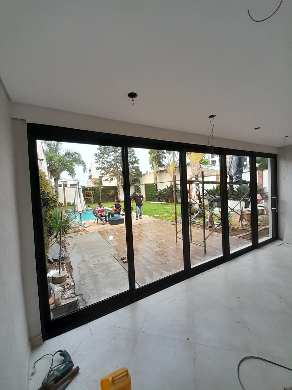 Sliding glass enclosure with black aluminum frame opening to the garden · MÁS VIDRIOS