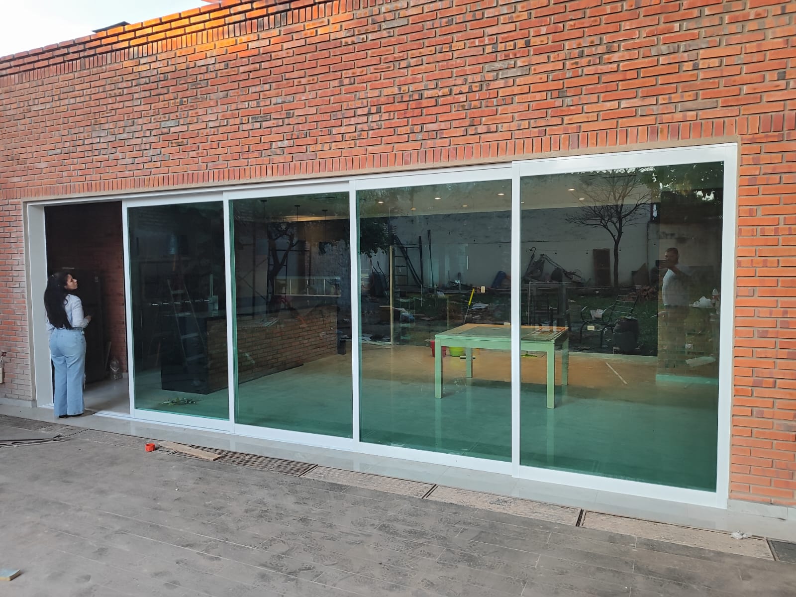 Vidriera corrediza de gran formato en fachada de ladrillo visto · MÁS VIDRIOS